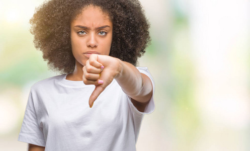 年轻的非洲美国妇女在孤立的背景上看起来不高兴和愤怒，表现出拒绝和消极的拇指向下的手势。 不好的表情。