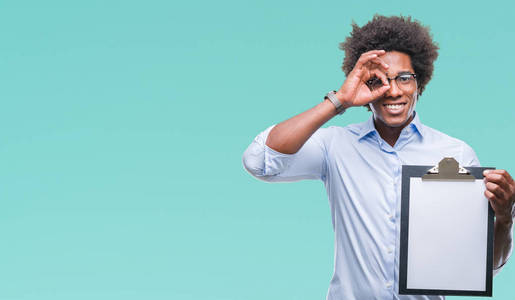 美国黑人男子拿着剪贴板在孤立的背景上，快乐的脸微笑，做好的标志，用手盯着手指看。