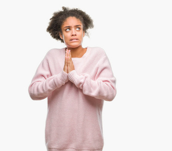 年轻的非洲美国妇女穿着冬季毛衣，在孤立的背景下乞讨和祈祷，双手一起祈祷，脸上充满希望的表情，非常情绪化和担忧。 请求原谅。 宗教