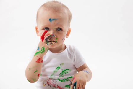 可爱的小婴儿绘画与画笔和彩色颜料在白色背景