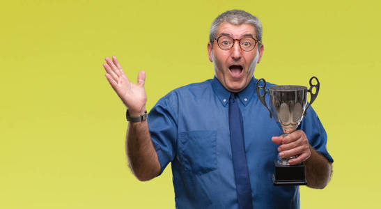 成功人士在孤立的背景下捧着奖杯,非常高兴和兴奋,胜利者的表情庆祝