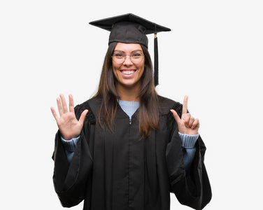年轻的西班牙裔妇女戴着毕业帽和制服，用手指七号，微笑着自信和快乐。