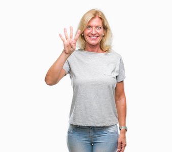 中年金发女人在孤立的背景上显示和指着第四个手指，同时微笑自信和快乐。