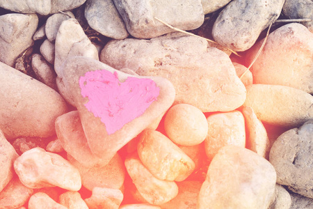 在许多小石头的背景上涂上口红的粉红色心脏