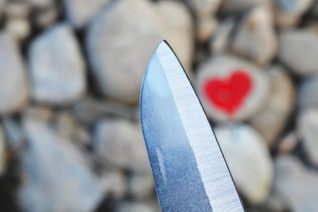 切割刀跳水粉红色的心涂上口红在一块石头上。 爱情结束的象征和两个人分手和离婚
