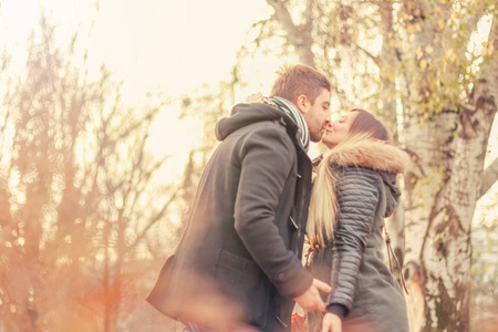 恋爱中的情侣秋男在公园里亲吻一个女人落叶美丽的秋日