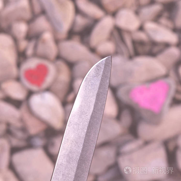 切割刀跳水粉红色的心涂上口红在一块石头上.