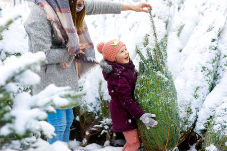可爱的小微笑的孩子女孩和母亲在圣诞树市场上