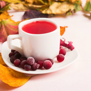 秋天的构图，红色健康蔓越莓热饮料和干饰叶粉色背景方形拍摄