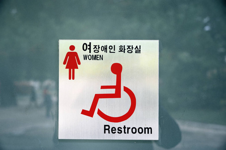 s restroom sign outdoors with text in English and Korean languag