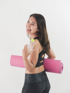 快乐的亚洲女人拿着一瓶水和粉红色瑜伽垫，生活方式的概念。