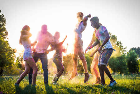 一群快乐的朋友在公园里玩霍利色年轻人在霍利节上玩，关于乐趣乐趣和年轻一代的概念