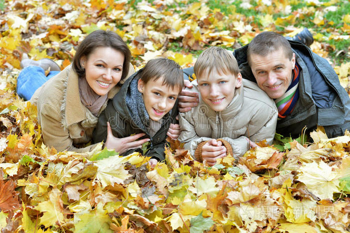 幸福的一家人躺在秋天的公园里
