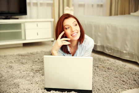 快乐的女人躺在地上拿着笔记本电脑