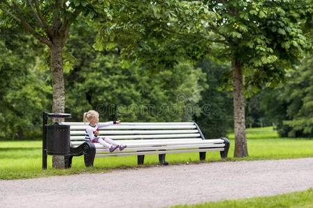 坐在公园长凳上的金发小女孩图片