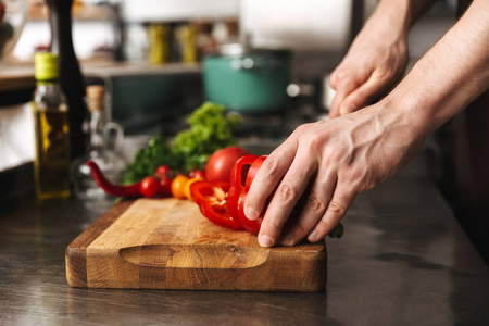 在厨房里,厨师用手在切菜板上切菜照片