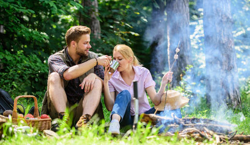 远足和野营的食物。情侣坐在篝火旁吃小吃和饮料。情侣在爱野营森林远足。远足小吃和饮料。远足野餐。夫妇休息吃自然背景