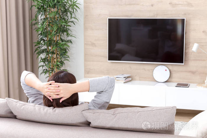 年轻的女人在房间里看电视