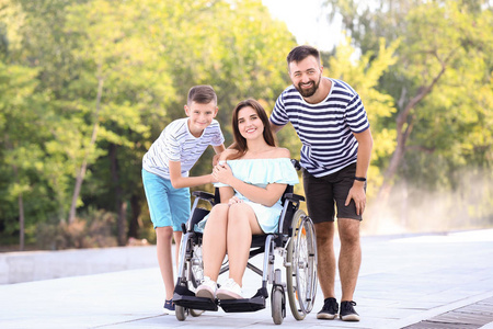 轮椅上的年轻女子和她的家人在户外散步