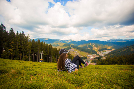 徒步旅行者女人的后景躺在山顶的草地上。 旅行概念