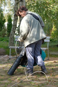 一个女人用吸尘器清洁树叶