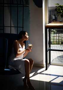 坐在椅子上的女人, 在阳光下享受第一个清晨的咖啡。完美的早晨与咖啡。女人在家的椅子上放松。旳茶道的女孩。漂亮女人喝日本茶