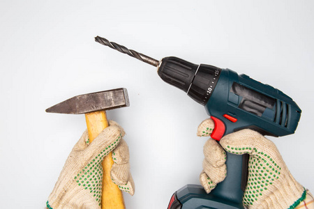 人手用无绳电钻和锤子在白色背景照片