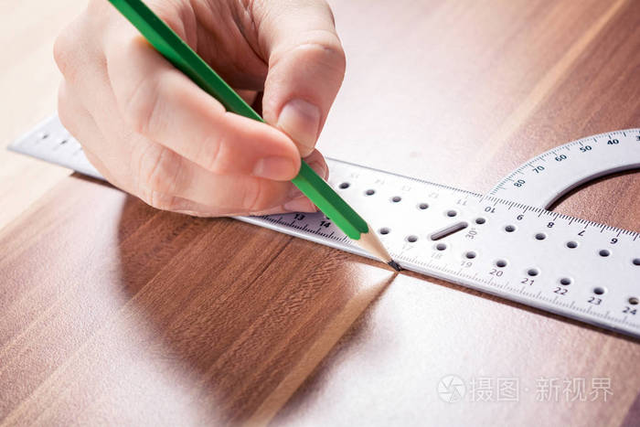 木匠使用量角器和在测量点用铅笔在木板上做标记