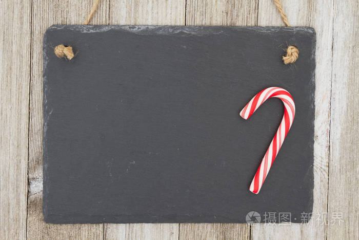 旧时尚圣诞挂黑板背景复古黑板与糖果挂在风化木材背景与复制空间为您的信息
