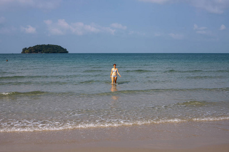 在白沙滩上走出海水的女孩。 热带海滨景观与孤独的游客。 暑假唯一的旅行者。 天堂岛。 绿松石海和白沙滩。 美丽的海景