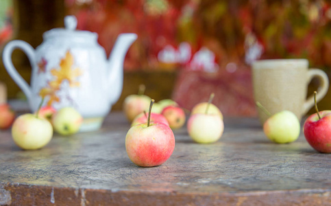 一杯带秋叶和苹果的茶在木桌上。 秋天的花园