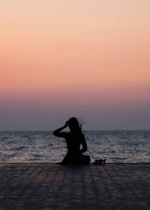 一个女孩在日落背景(日出)上的剪影在海平线上. 夏天在海滩上散步.