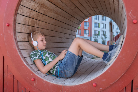 微笑的男孩与智能手机和耳机听音乐或玩游戏