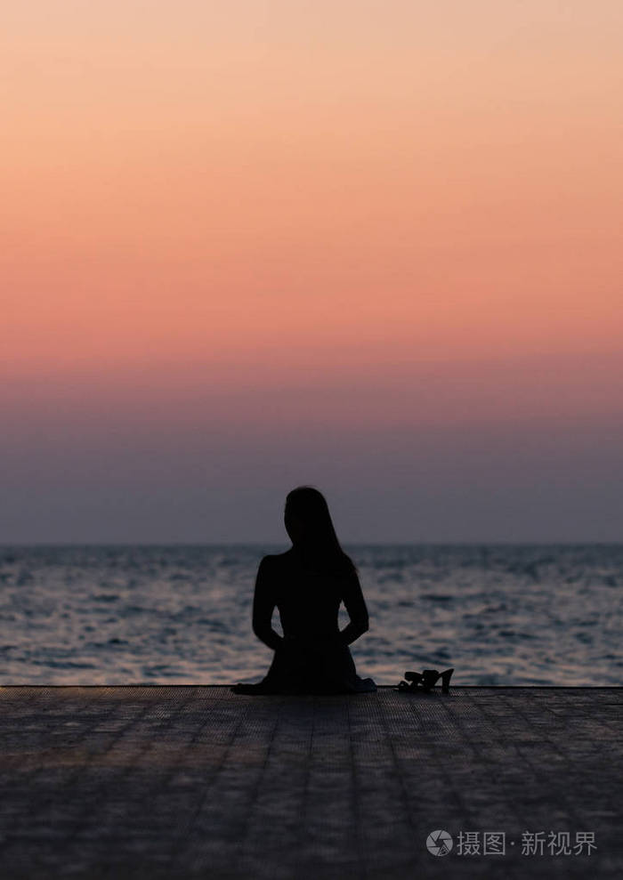 一个女孩在日落背景(日出)上的剪影在海平线上. 夏天在海滩上散步.