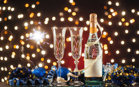 圣诞节和新年庆祝香槟。 新年假期装饰表。 两个香槟杯，背景是深色的，金色的光芒和波克