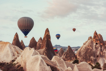 热气球在土耳其卡帕多西亚的岩石景观上空飞行。 山谷峡谷山位于戈雷姆国家公园火山山之间。