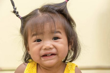 一个十个月大的女孩穿着一件黄色外套，开心地笑着，只有四颗牙齿，她流口水。
