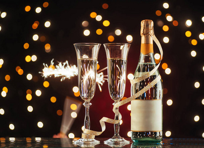 圣诞节和新年庆祝香槟。 一双长笛和一瓶香槟，在黑暗的背景下，金色的光芒和波克
