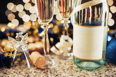 圣诞节和新年庆祝香槟。 一双长笛和一瓶香槟，在黑暗的背景下，金色的光芒和波克