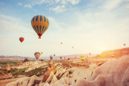 热气球飞越土耳其的岩石景观。 卡帕多西亚与其山谷峡谷丘陵之间的火山山在戈尔梅国家公园。