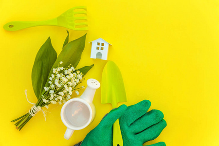平躺园艺工具浇水可以铲耙手套花和玩具屋在黄色五颜六色的时尚背景。 春季或夏季花园生态自然农场园艺爱好概念