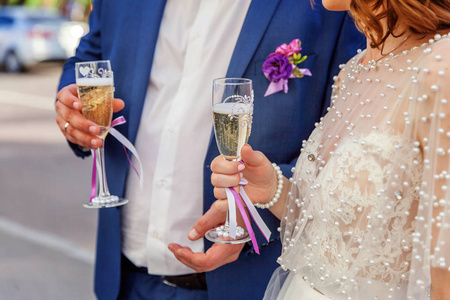 婚礼庆典。 新娘和新郎拿着香槟酒杯，用酒杯紧紧地握着祝酒的手