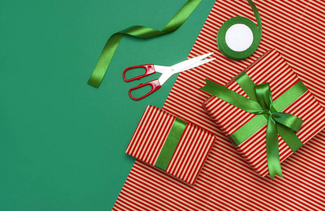 礼品盒包装纸剪刀丝带绿色背景。 节日背景祝贺礼物包装圣诞节和新年主题。 平躺式顶部视图