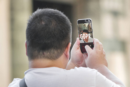 男人看着智能手机上的自拍照片，他的脸隐藏在一个铭文GDP R后面。 数据保护条例。 网络安全和隐私。