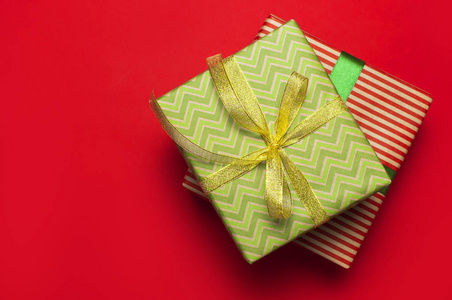 礼品盒与绿色丝带在红色背景顶部视图平躺。 节日概念新年或圣诞礼品盒赠送圣诞假期。 恭喜背景空间的文本。