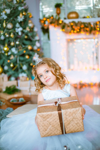 一个可爱的小女孩，家里有一头金发，靠近一棵圣诞树，里面有礼物花环和装饰的壁炉