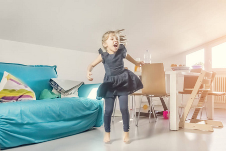 穿着蓝色裙子的金发小女孩正在房间里跳舞照片