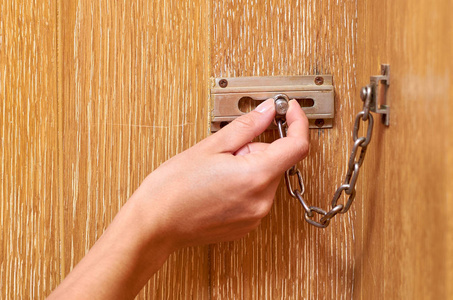 金属链锁，手在木制前门。