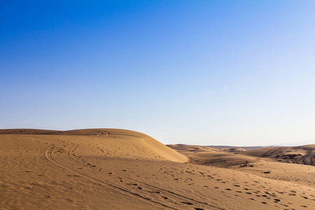日落时，伊朗卡山附近马拉贾布沙漠中的沙丘，沙丘上可以看到脚和轮胎的路径。 马拉沙漠是该地区的主要地标之一