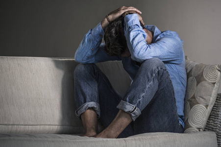 生活方式肖像年轻,有魅力,英俊,悲伤,拉丁男人,疲惫和沮丧地坐在家里